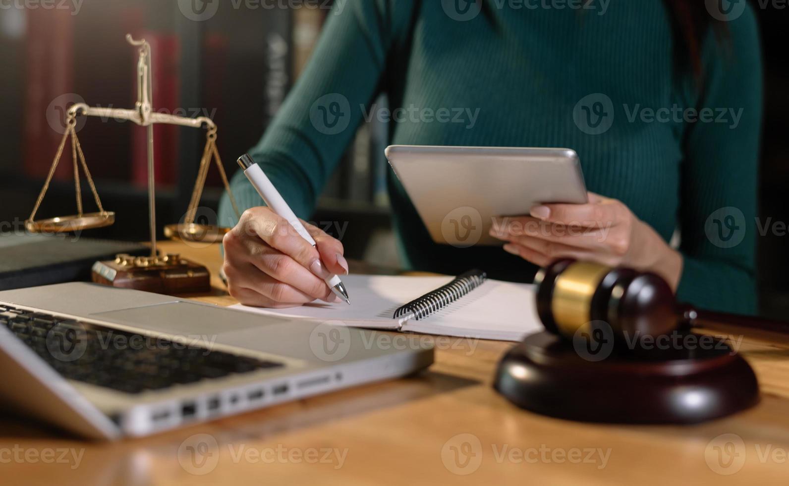 conceito de justiça e direito. juiz masculino em um tribunal o martelo, trabalhando com tablet na mesa de madeira foto