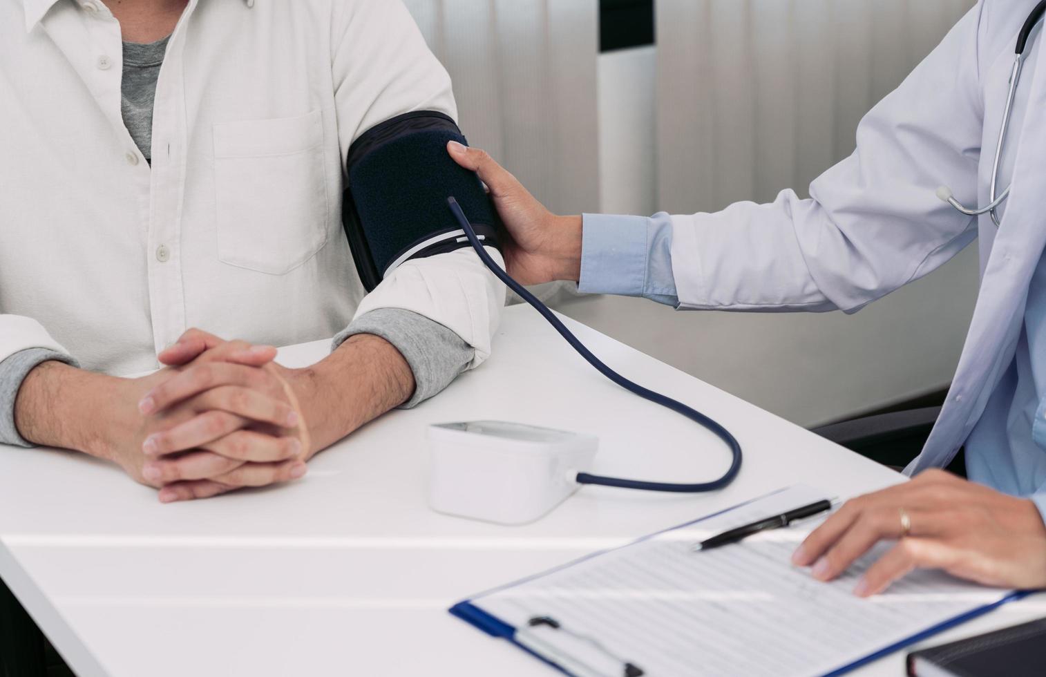 médico asiático está usando o monitor de pressão arterial de um paciente no momento de seu check-up anual e explica sua pressão arterial. foto
