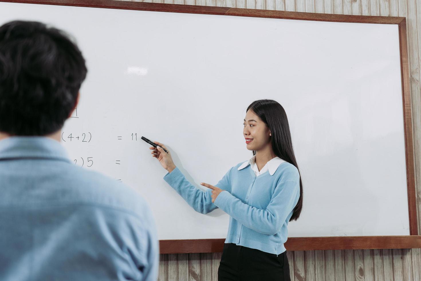 jovem professor asiático ensinando alunos em sala de aula. foto