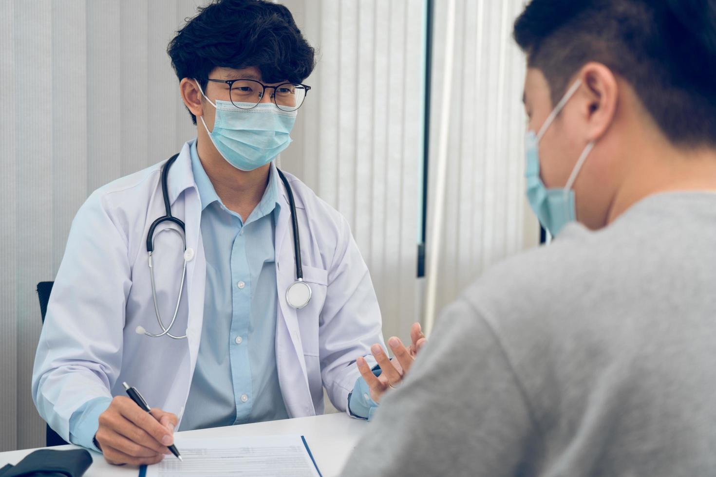 os médicos estão explicando o tratamento da doença de um paciente usando uma máscara durante a epidemia. foto