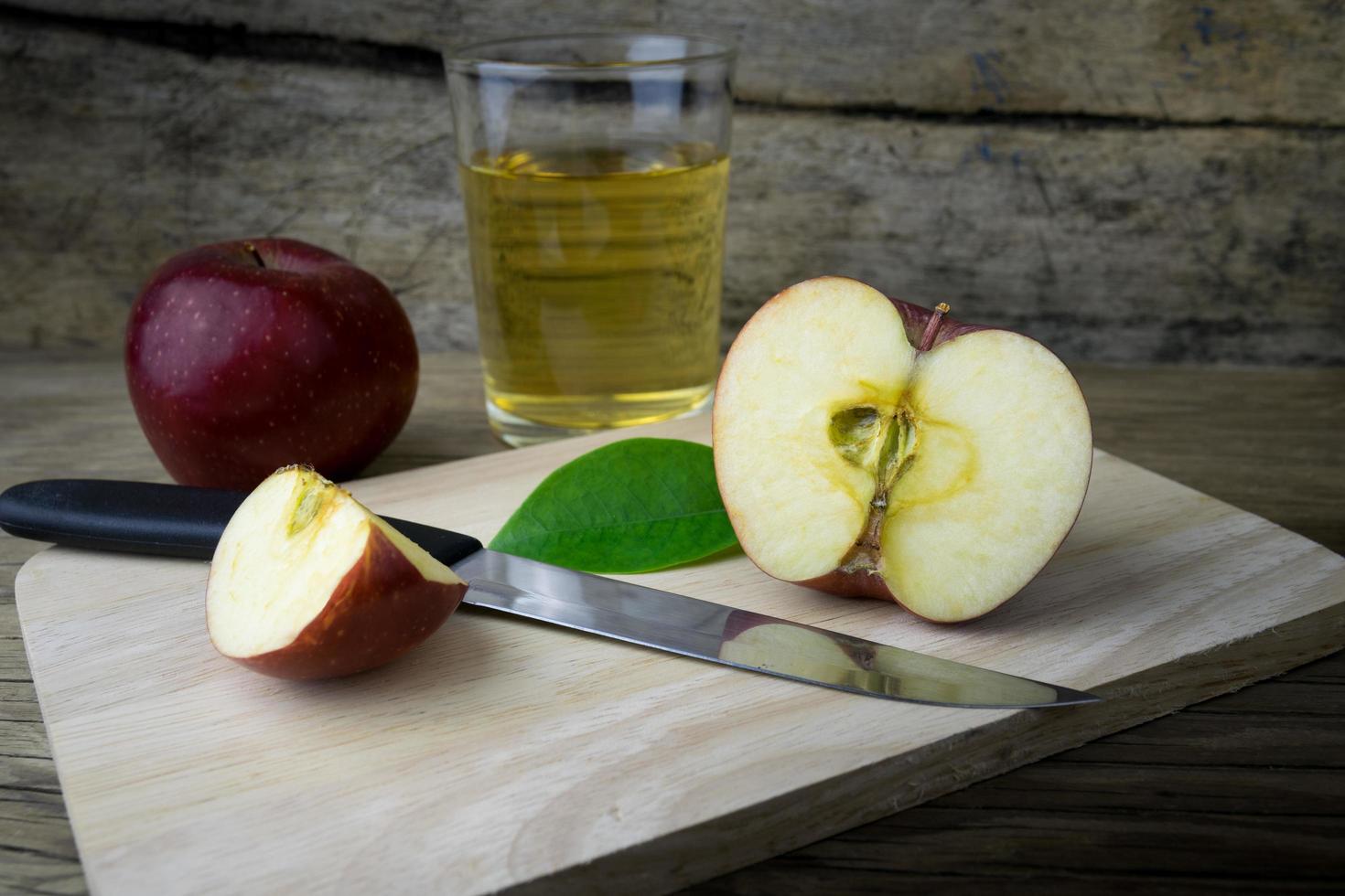 suco de maçã e maçãs em uma mesa de madeira foto