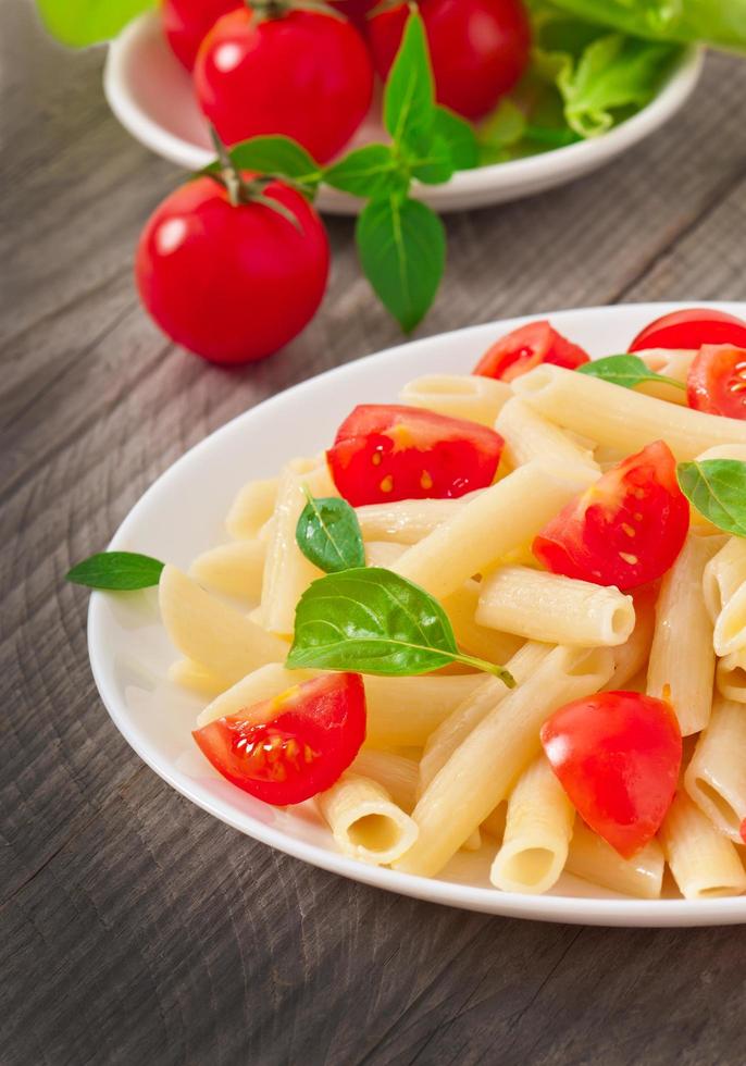 salada de macarrão com tomate cereja e folhas de manjericão fresco foto