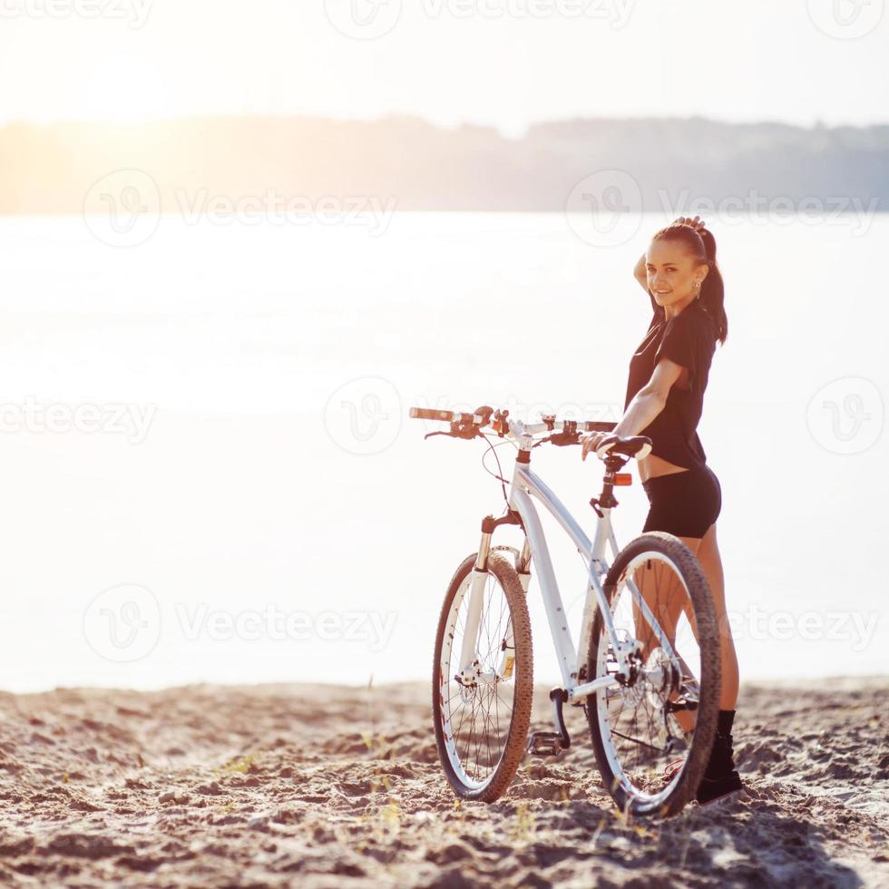 mulher de bicicleta perto da água foto