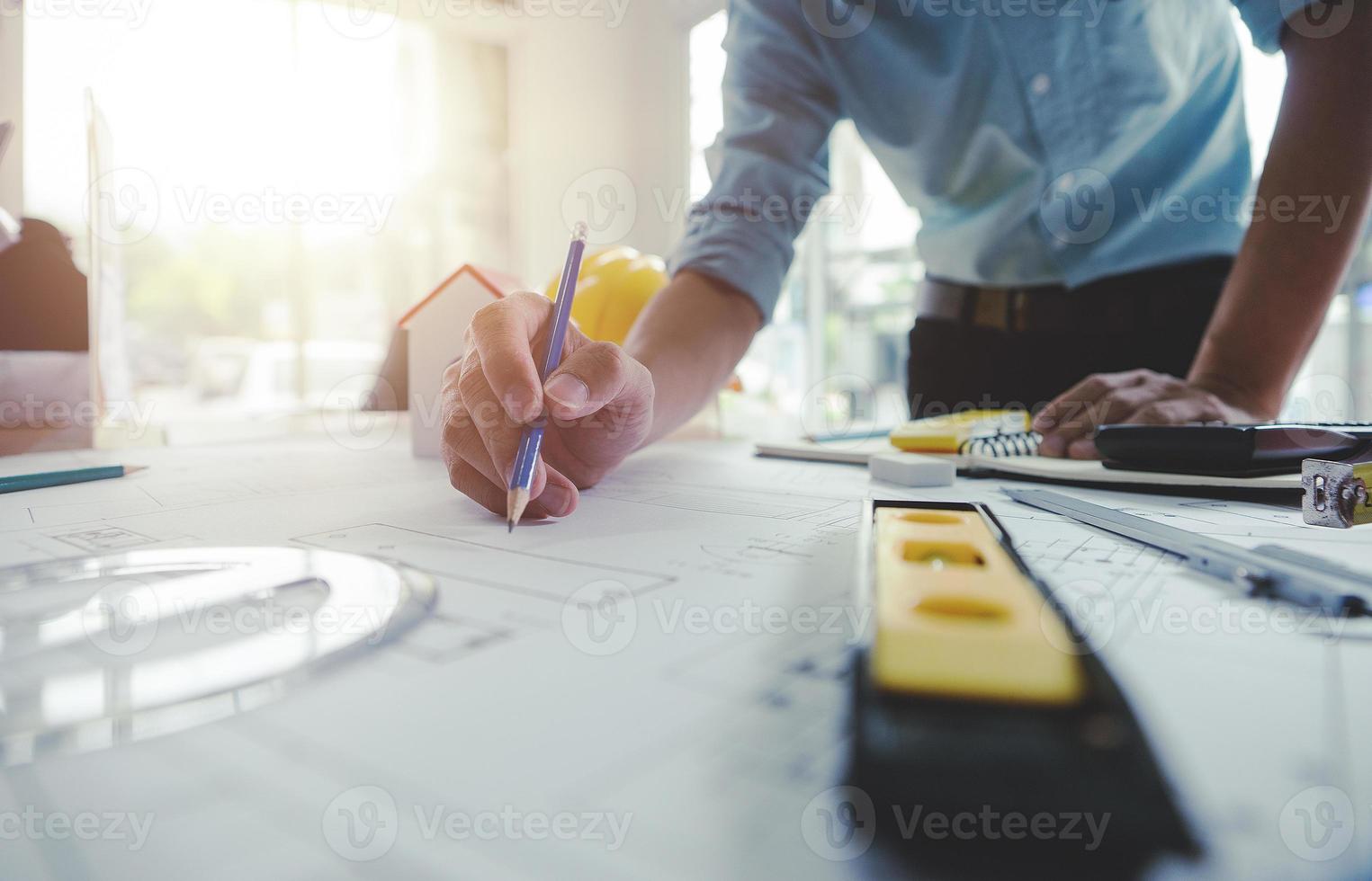 mãos de arquiteto ou engenheiro usando lápis trabalhando com planta na mesa no escritório. ferramentas de engenharia e conceito de construção. foco de arquiteto e negócio concept.selective, efeito vintage. foto