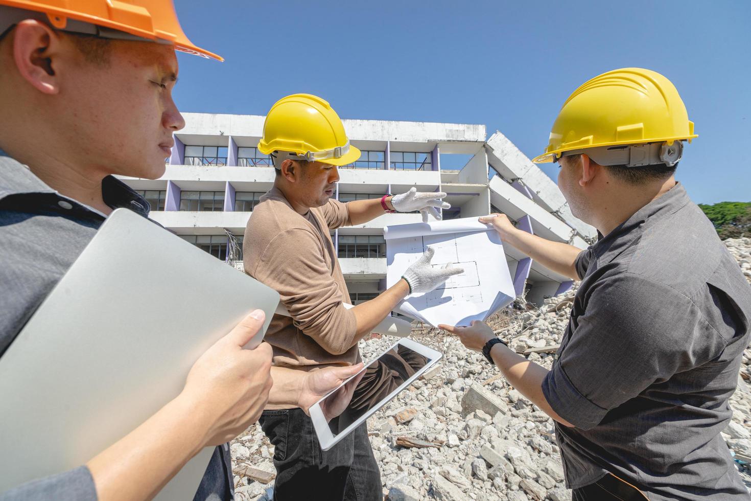 equipe de engenheiros e trabalhadores verificando o plano de construção de demolição e inspecionando no local. foto