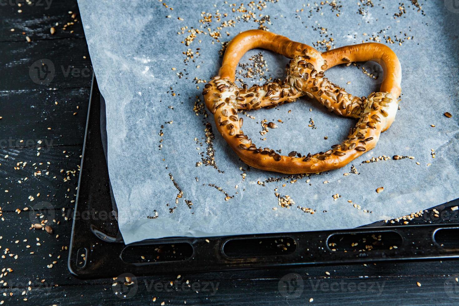 pretzels macios caseiros preparados na hora. diferentes tipos de bagels assados com sementes em um fundo preto. foto
