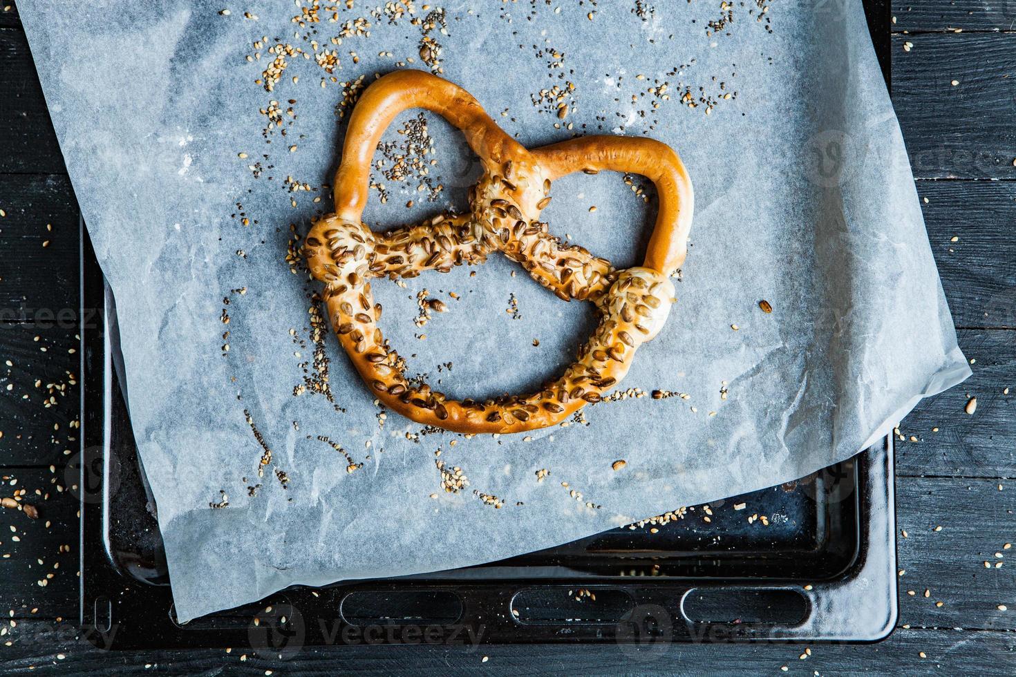 pretzels macios caseiros preparados na hora. diferentes tipos de bagels assados com sementes em um fundo preto. foto