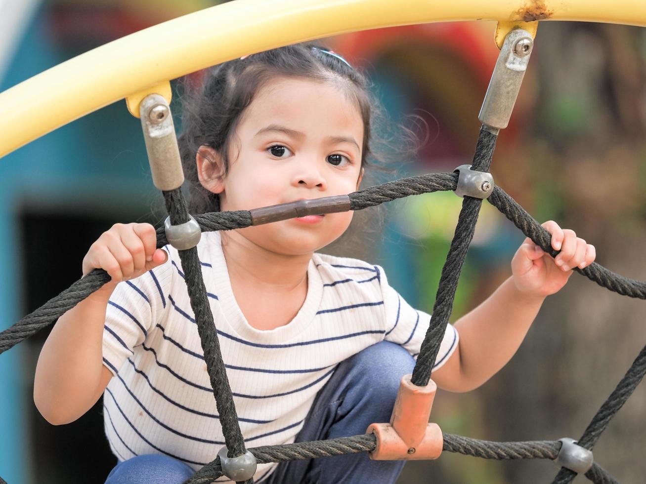jovens garotas asiáticas estão se divertindo escalando em redes de corda em um playground foto