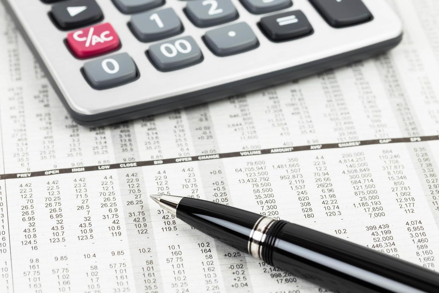 caneta e calculadora no jornal financeiro de detalhes do preço das ações foto