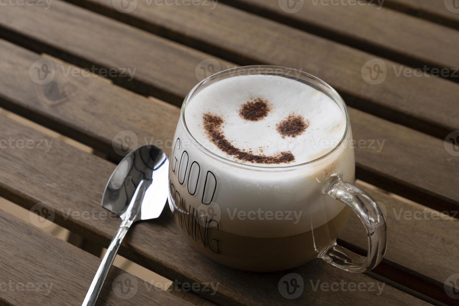 café com leite quente com arte de café com rosto sorridente foto