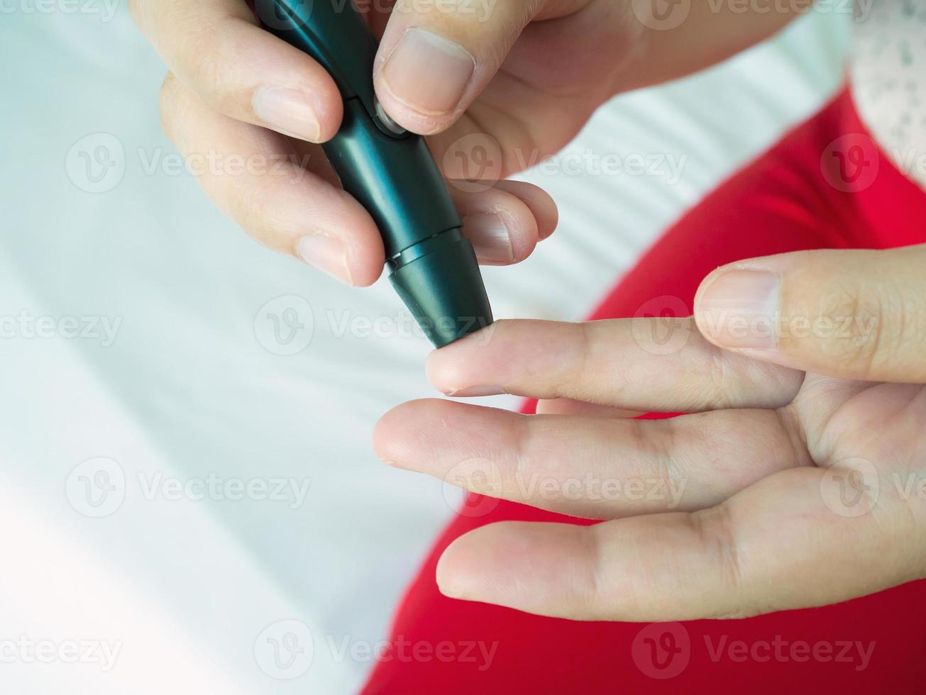 mulher usando lancelet no dedo, teste de diabetes foto