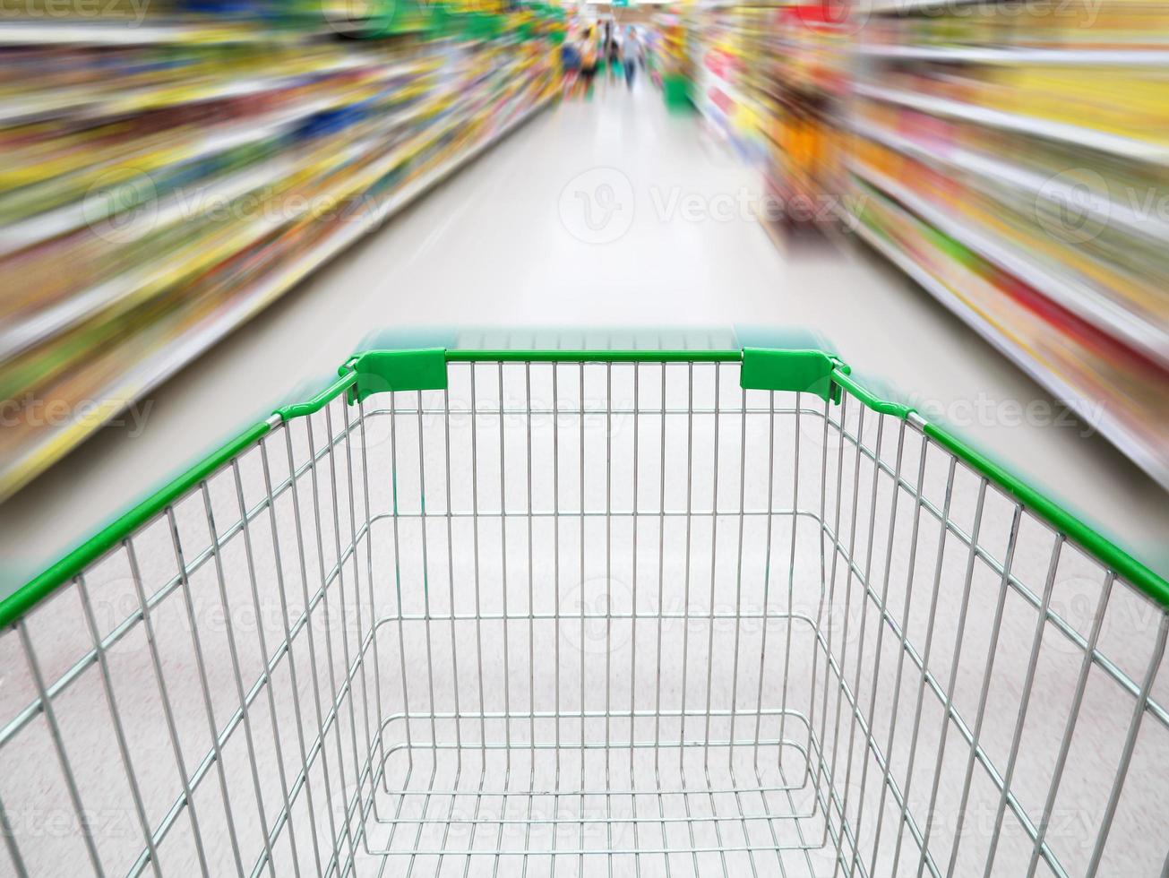 corredor do supermercado com carrinho de compras verde vazio foto