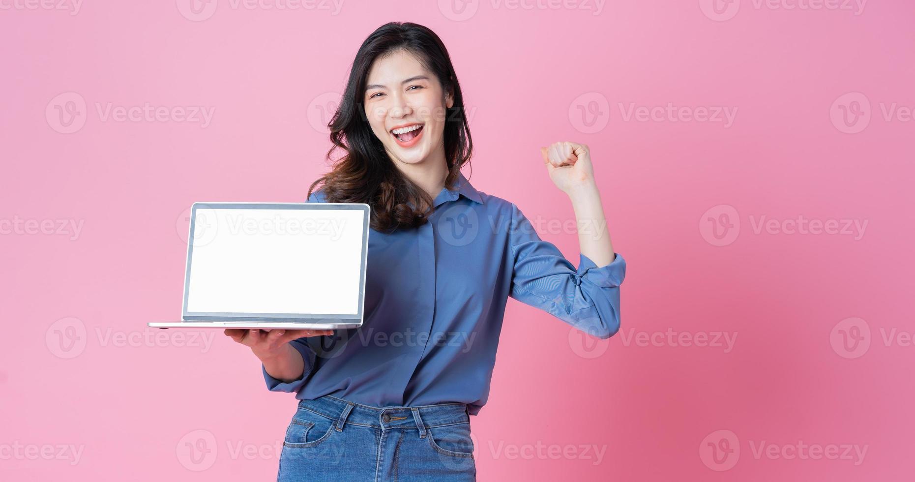 jovem empresária asiática usando laptop em fundo rosa foto