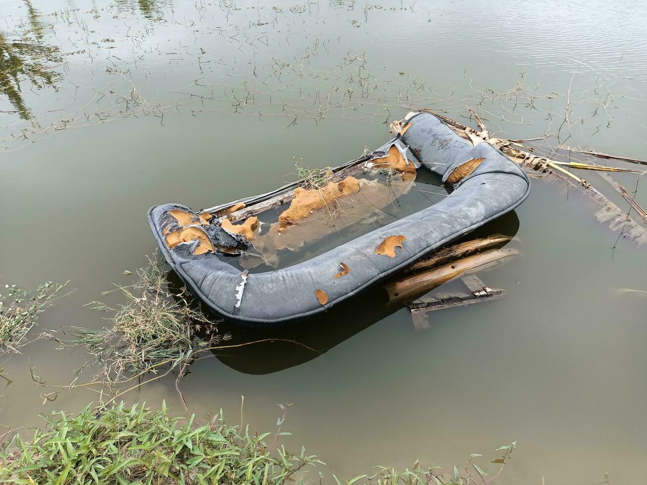 foto dos destroços de um sofá quebrado submerso na água.