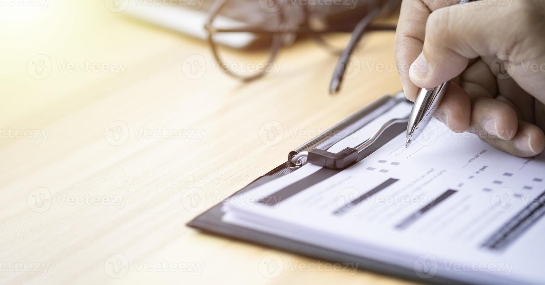 mão usando caneta de escrita com questionário ou pergunta de pesquisa de papelada preenchendo o documento de lista de verificação do formulário de informações pessoais da empresa de negócios foto