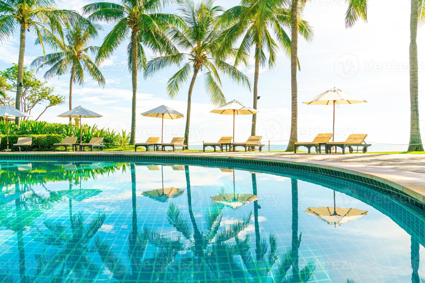 lindo guarda-sol e cadeira ao redor da piscina no hotel e resort foto