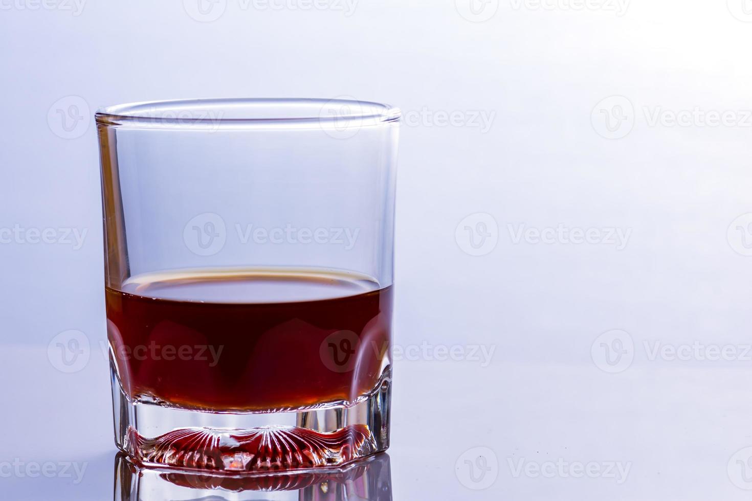 copo de uísque em uma mesa de vidro foto