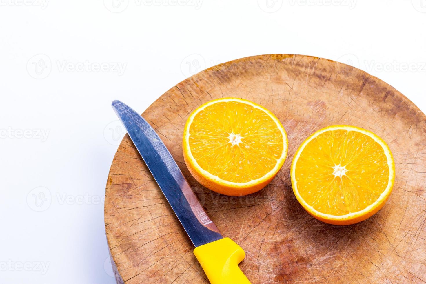 a laranja é metade da bola e facas colocadas na tábua de cortar no fundo branco foto