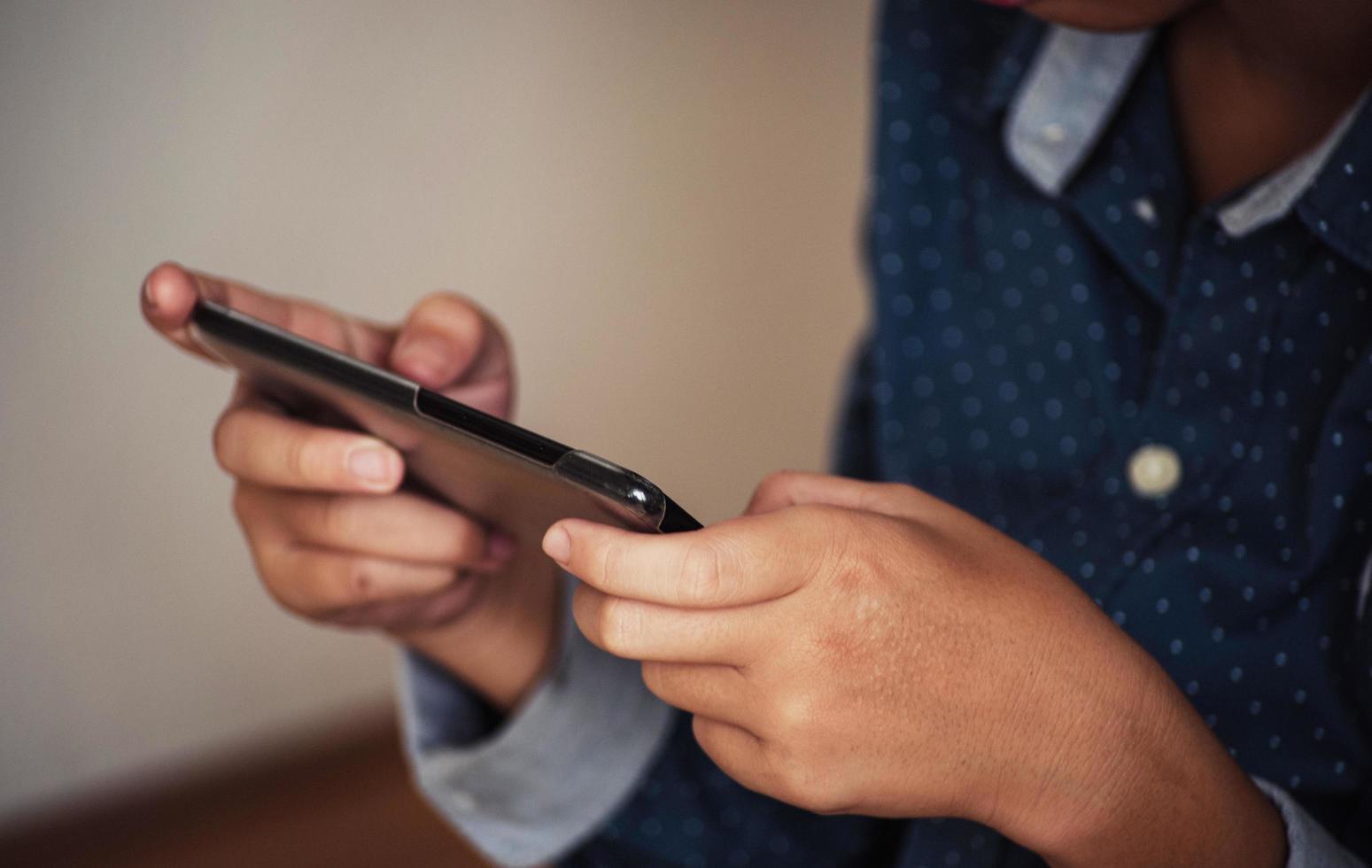 menino jogando em smartphones, mão de menino segurando um smartphone foto