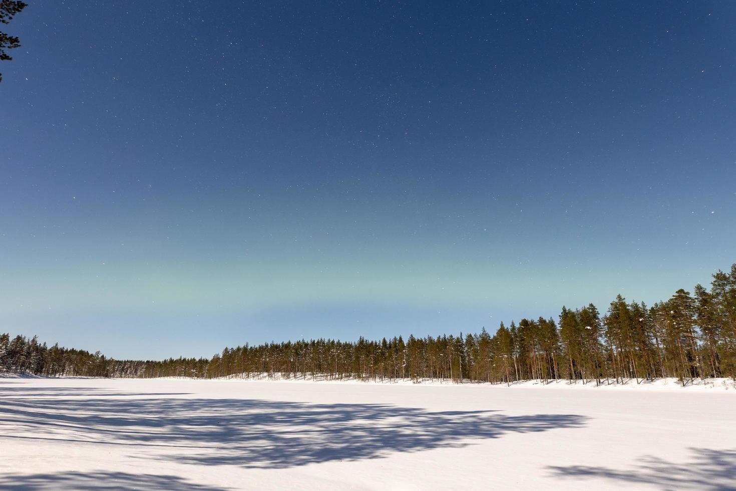 bela luz do norte aka aurora boreal e paisagem de inverno enluarada na finlândia foto