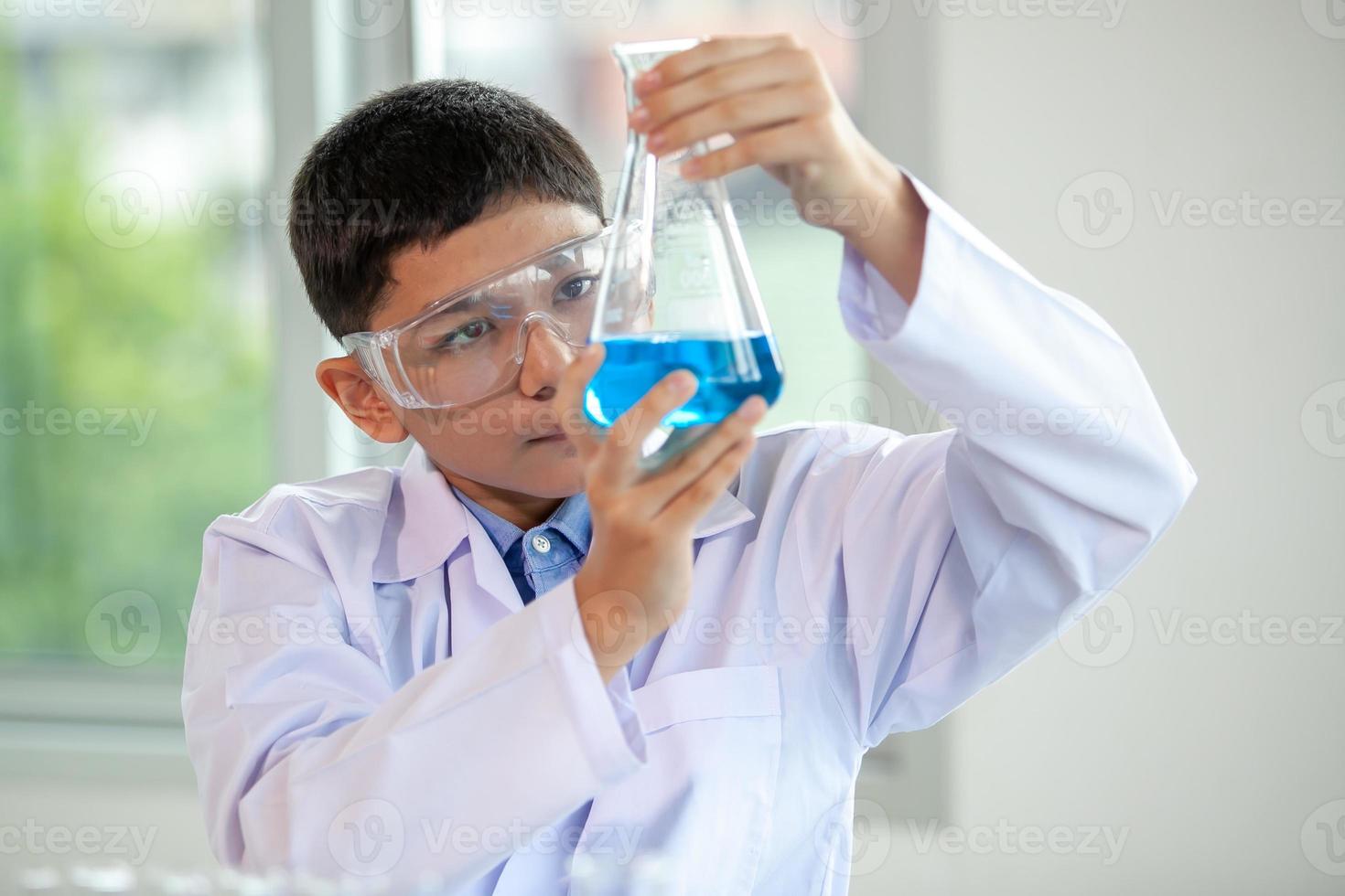 menino mistura produtos químicos em copos. crianças com tubo de ensaio fazendo experimento no laboratório da escola. foto