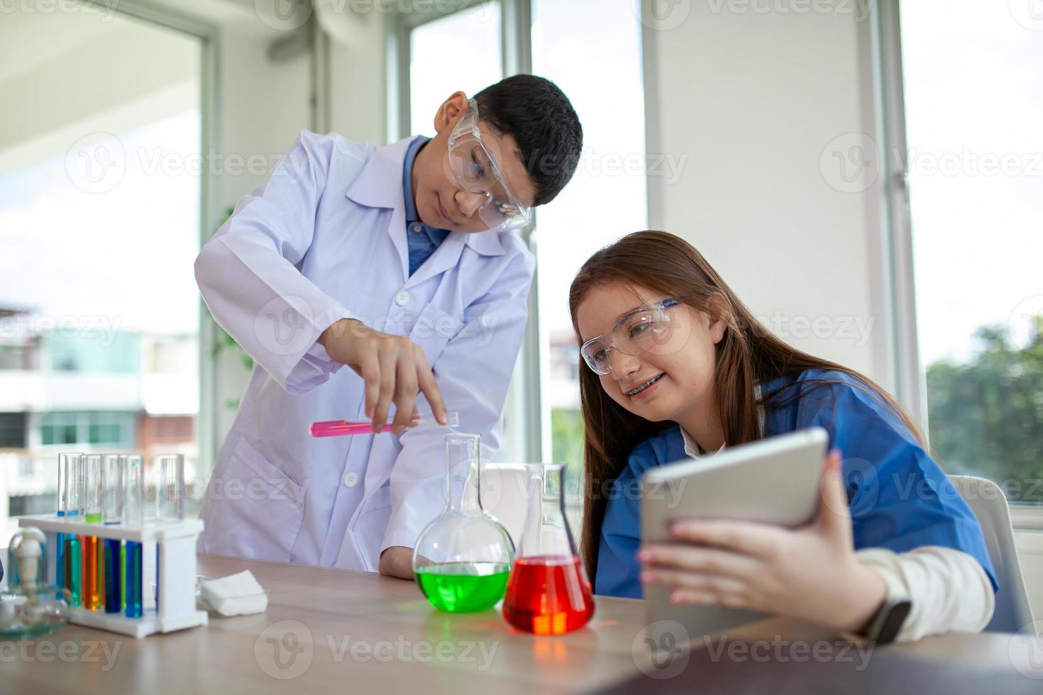 alunos misturam produtos químicos em béqueres. estudante de química mistura produtos químicos na aula de ciências foto