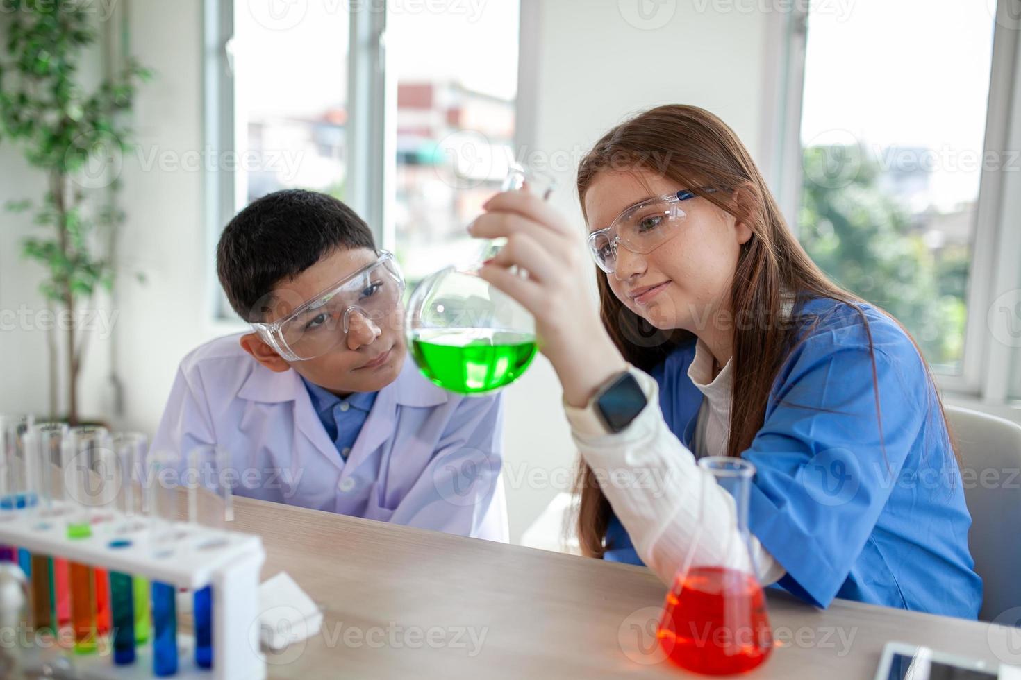 alunos misturam produtos químicos em béqueres. estudante de química mistura produtos químicos na aula de ciências foto