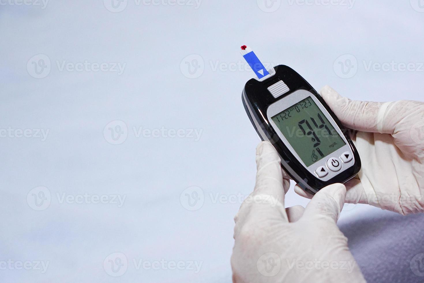 luvas de desgaste médico está verificando o nível de açúcar no sangue com medidor de glicose. foto