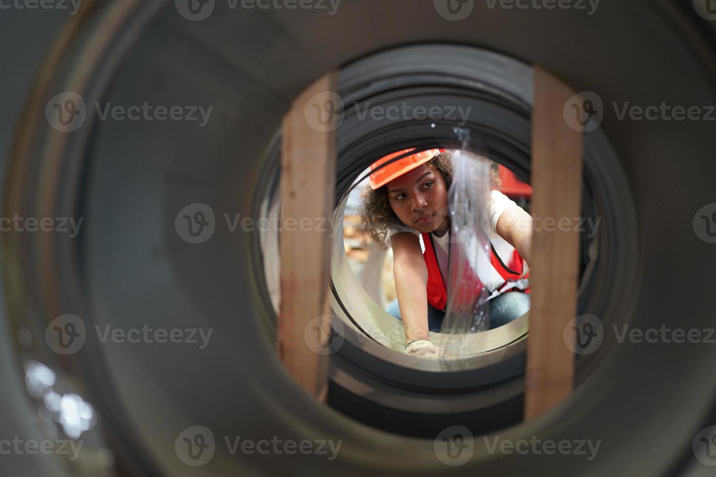 engenheira industrial feminina usando um capacete de segurança em pé em uma fábrica industrial pesada. a manutenção procurando trabalhar em máquinas industriais e verificar a configuração do sistema de segurança na fábrica. foto