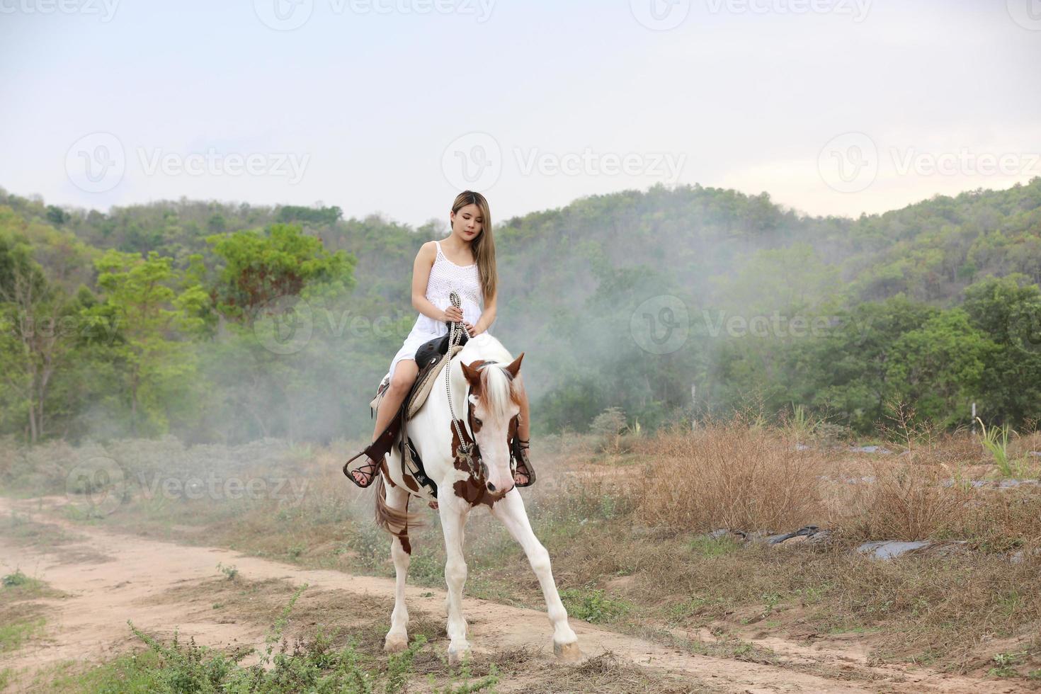 jovem e bonita com seu cavalo na luz do sol à noite. fotografia ao ar livre com garota modelo de moda. humor de estilo de vida foto