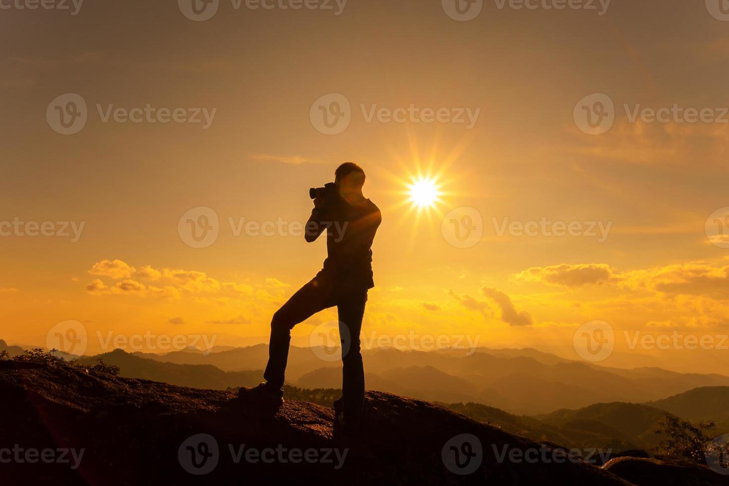 silhueta de um fotógrafo tirando foto da bela paisagem na montanha alta durante o momento do pôr do sol.