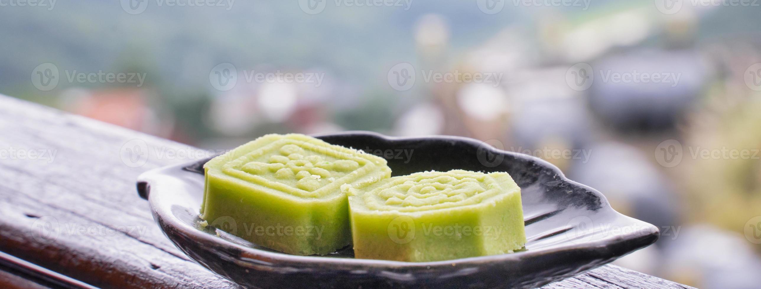 delicioso bolo de feijão verde com prato de chá preto na grade de madeira de uma casa de chá em taiwan com bela paisagem ao fundo, close-up. foto