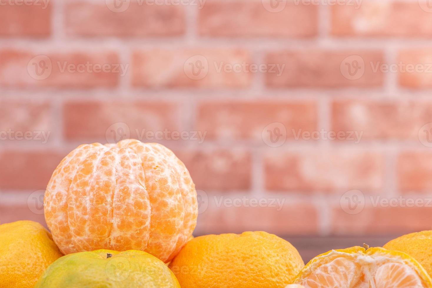 tangerinas descascadas em uma cesta de peneira de bambu na mesa de madeira escura com fundo de parede de tijolo vermelho, conceito de design de frutas do ano novo lunar chinês, close-up. foto