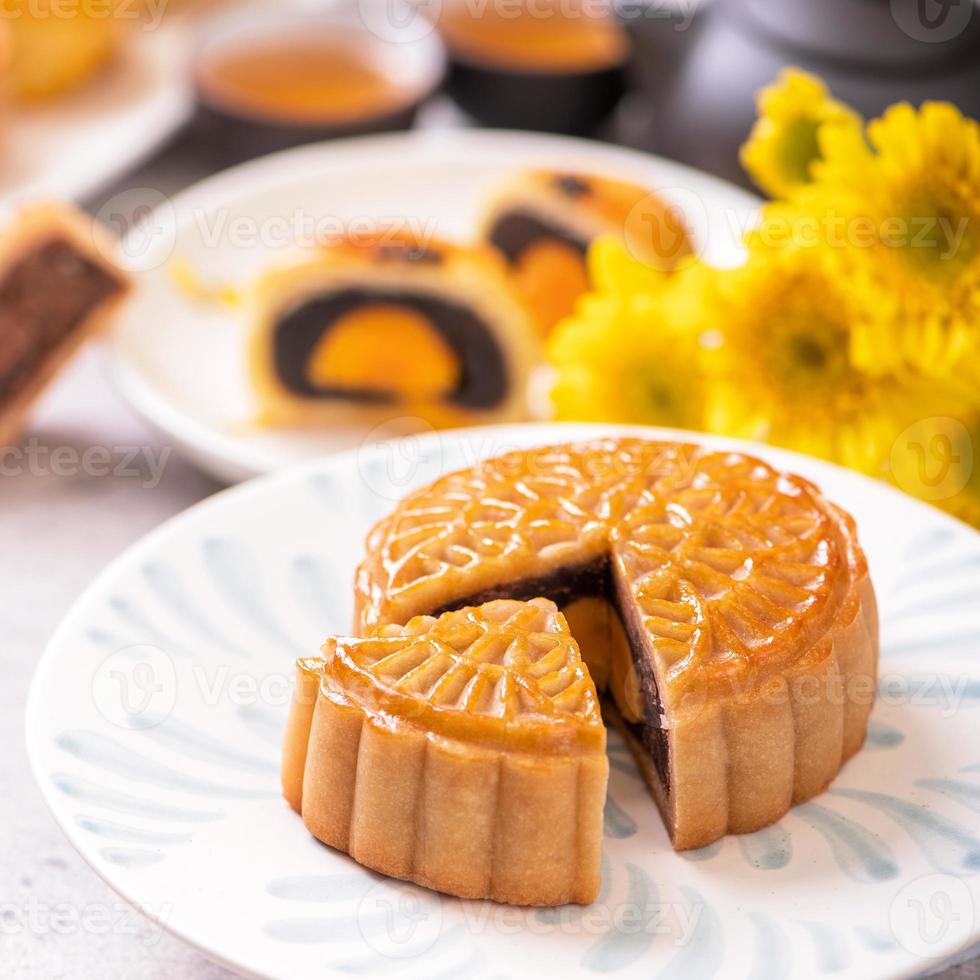 conceito de comida tradicional do festival do meio do outono - lindo bolo de lua cortada na placa padrão azul sobre fundo branco com flor, close-up, copie o espaço foto