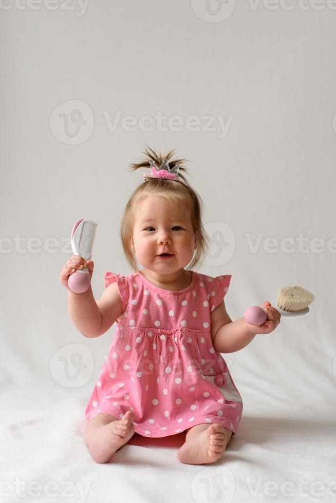 menina 6 meses de idade com um pente na mão em um fundo branco. foto