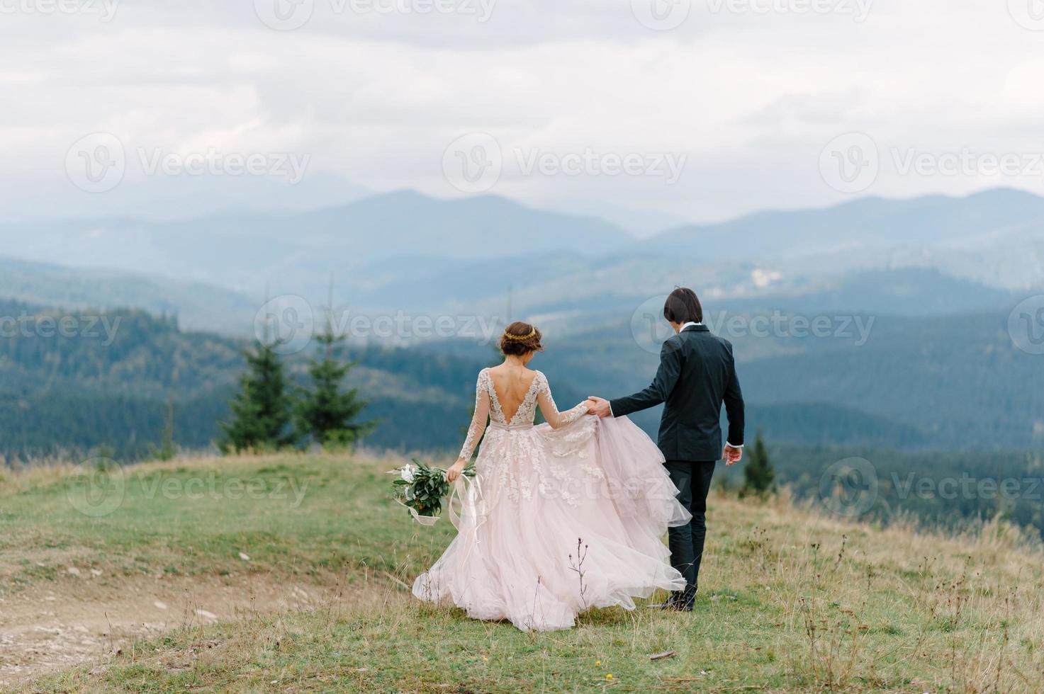 lindo casal de noivos beijando e abraçando perto da margem de um rio de montanha com pedras foto