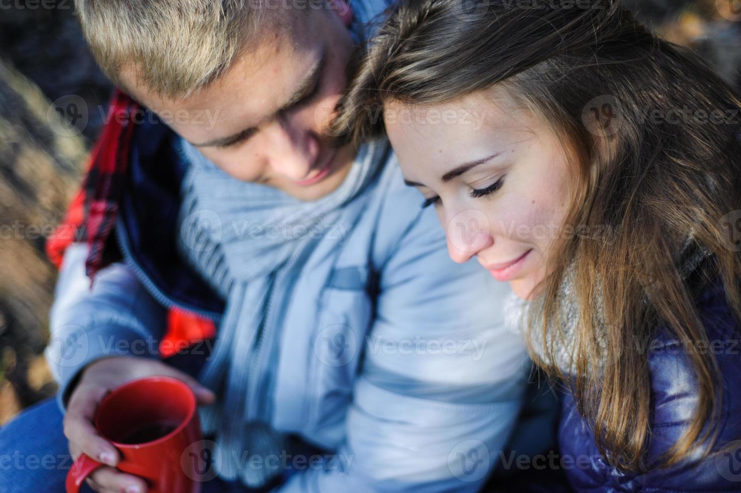 muito jovem casal relaxando perto da fogueira na floresta à noite foto