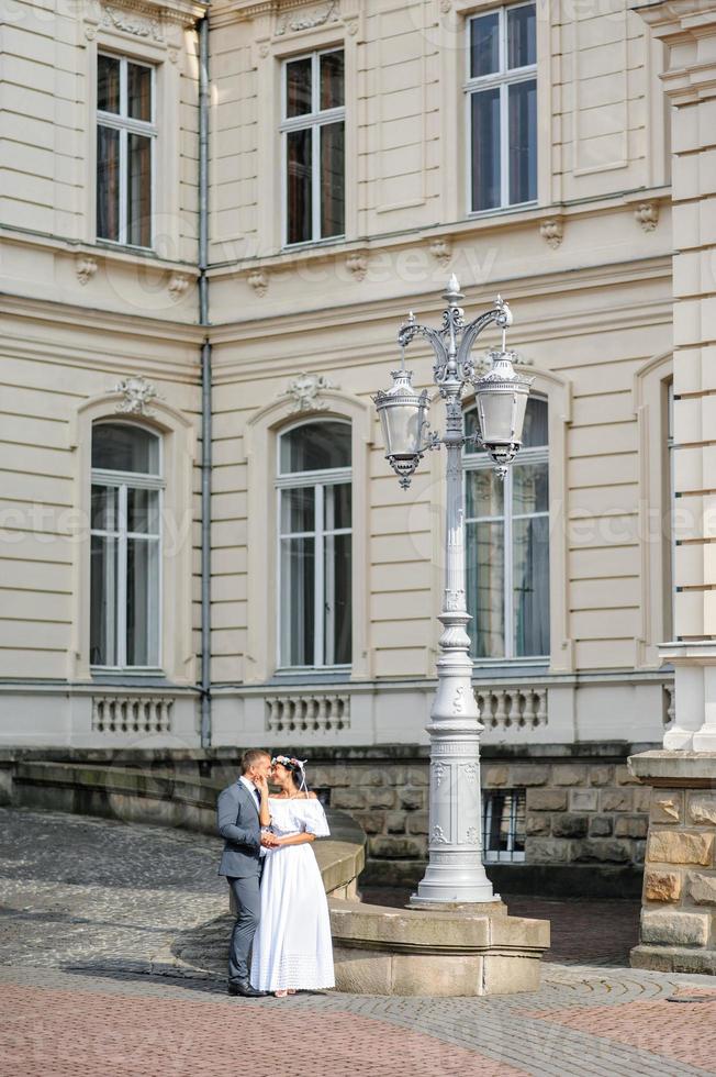 sessão de fotos de casamento no fundo do antigo prédio. o noivo observa sua noiva posando. fotografia de casamento rústica ou boho.