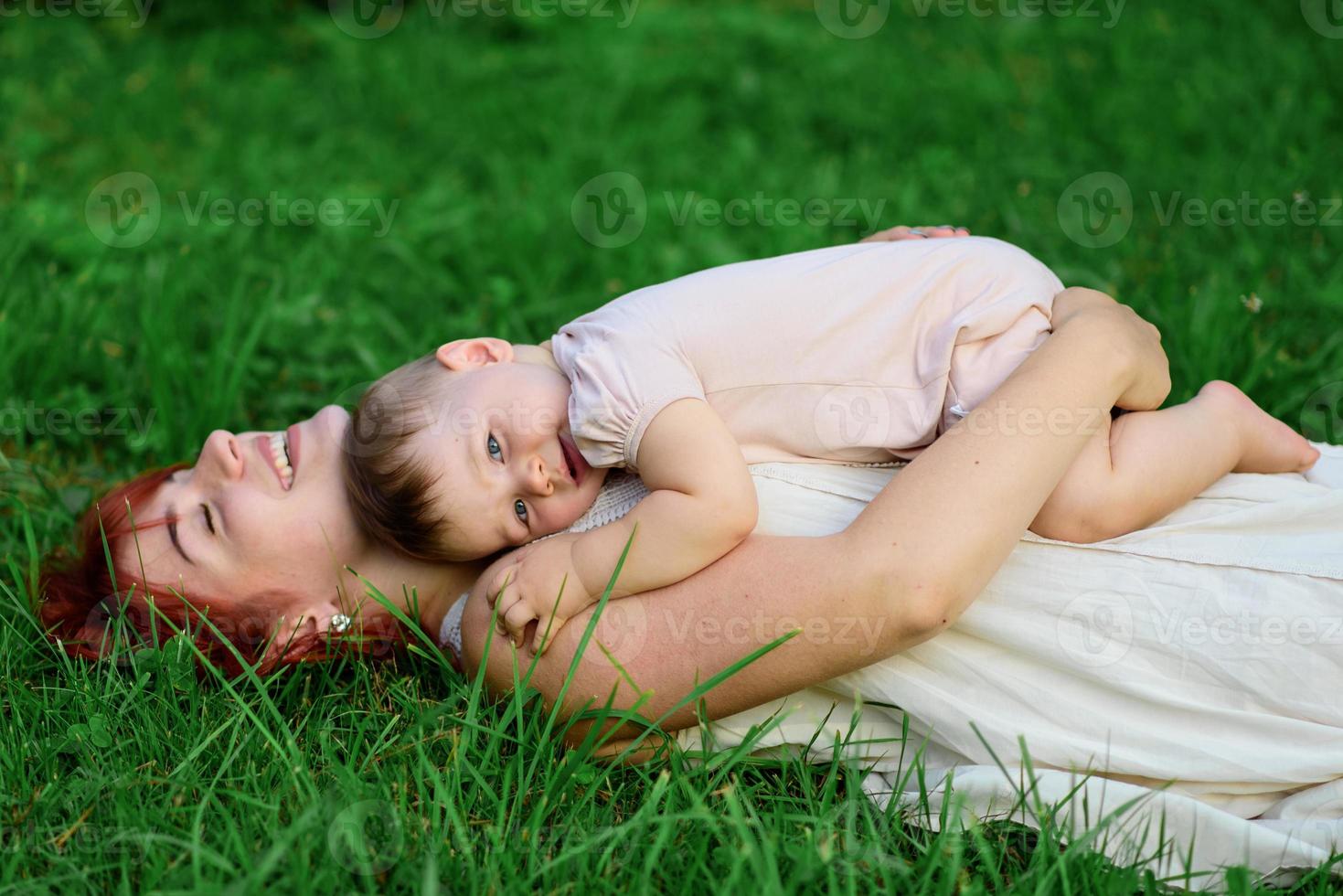 mãe abraça e brinca com sua filha de um ano enrolada em uma toalha após o banho. foto