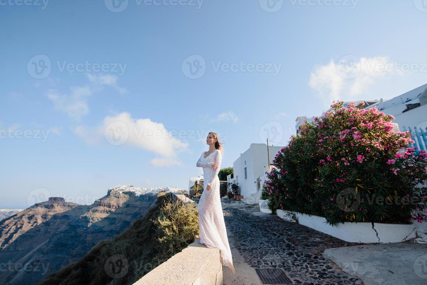 europa grécia santorini viagens férias. mulher olhando a vista no famoso destino de viagem. elegante jovem vivendo estilo de vida jetset chique vestindo vestido nos feriados. vista incrível do mar e caldeira foto