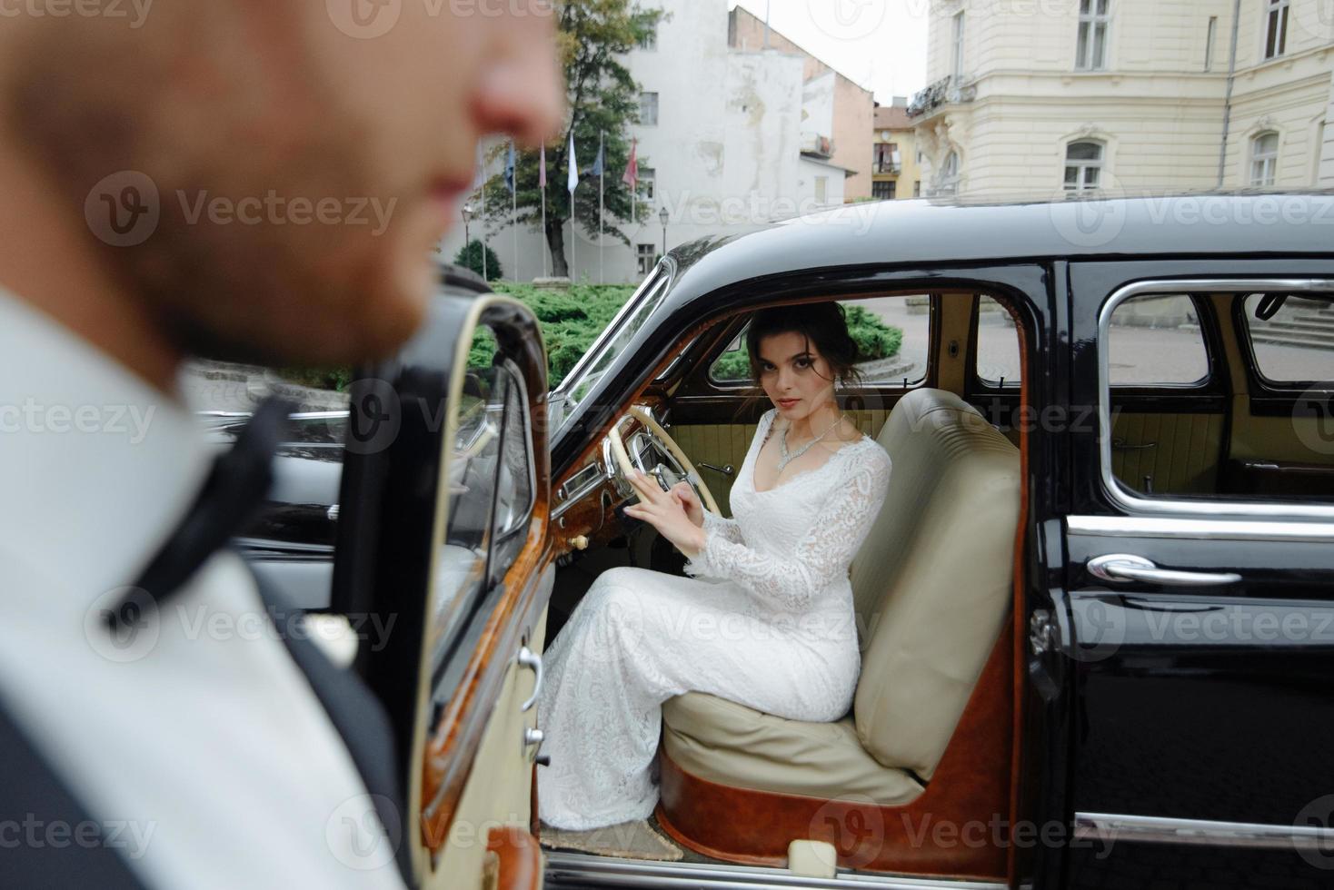 linda jovem noiva e noivo olhando de auto retrô foto