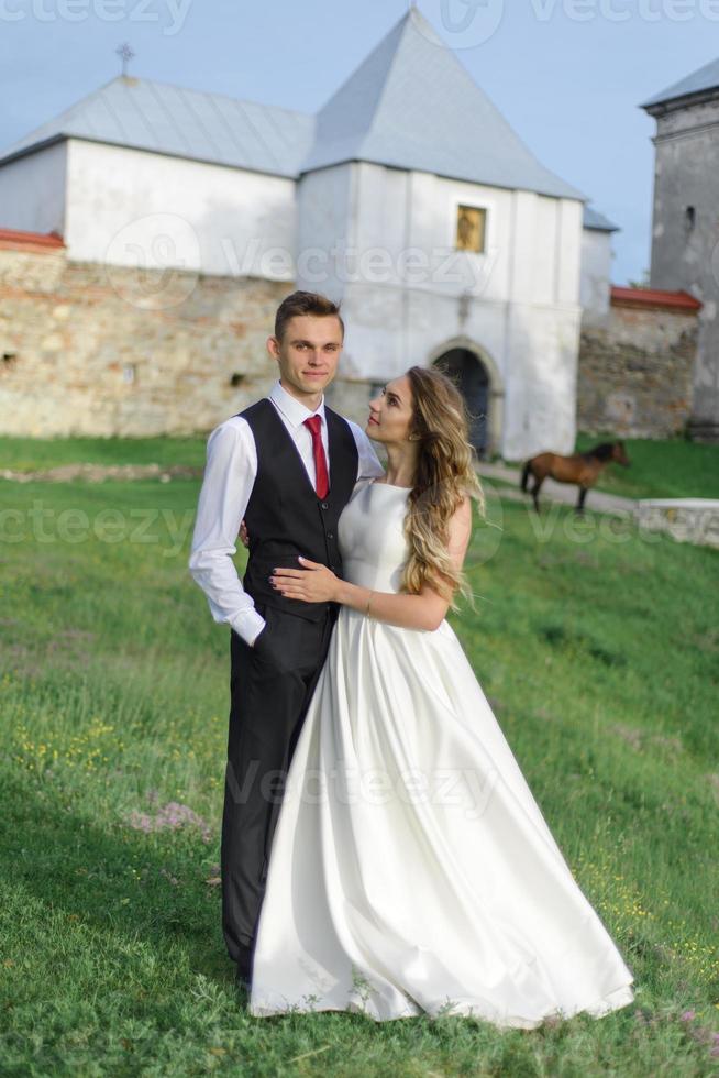 noivos em um campo de trigo. o casal se abraça durante o pôr do sol foto