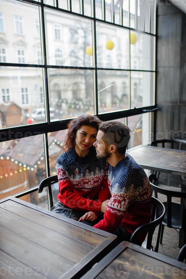 mulher encantadora feliz vestida de malhas conversando com seu namorado bonito passar um tempo em casa aconchegante, casal romântico apaixonado feliz por estar juntos celebrando férias de inverno de bom humor foto