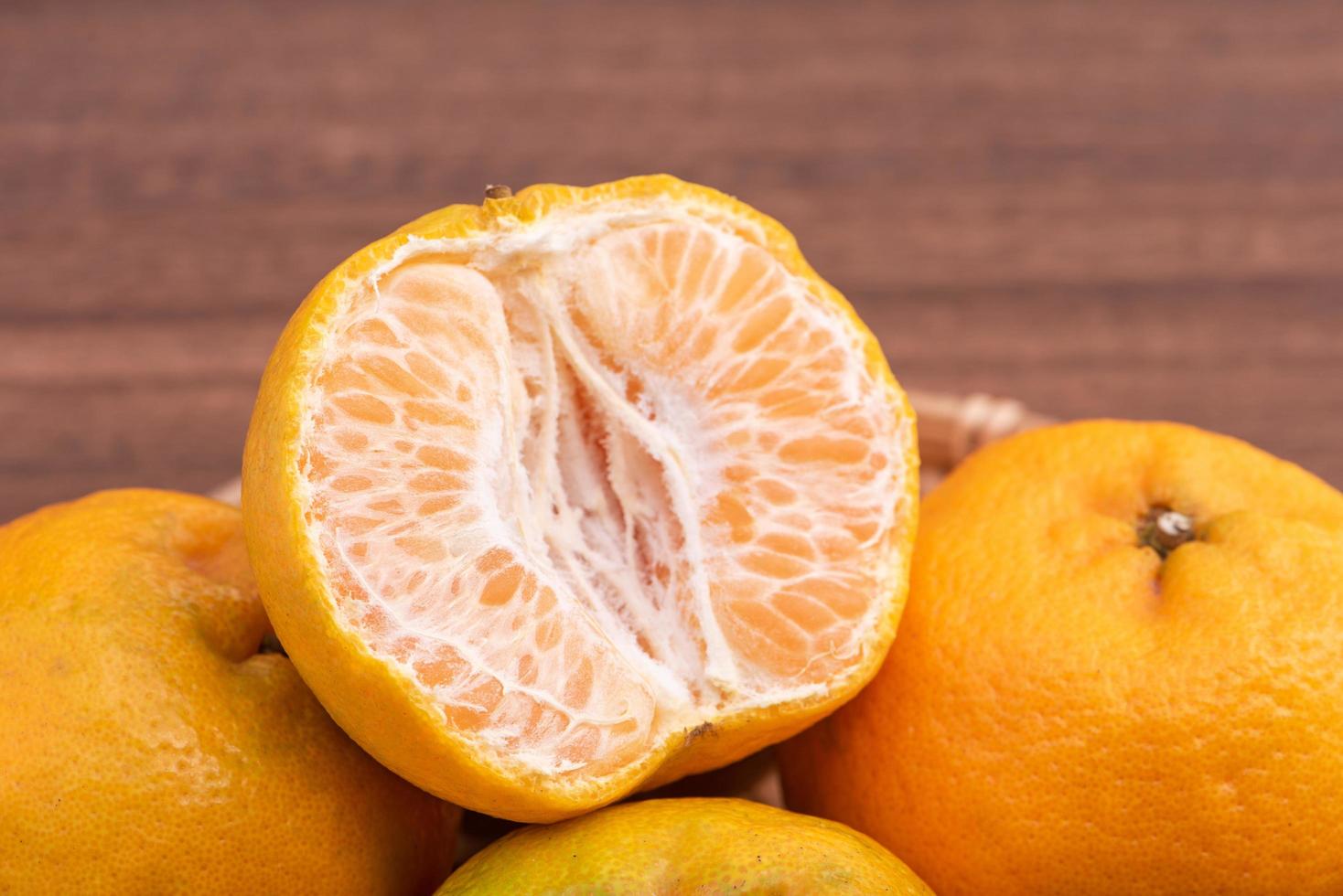 fresca, linda tangerina de cor laranja na peneira de bambu sobre a mesa de madeira escura. fruta sazonal e tradicional do ano novo lunar chinês, close-up. foto