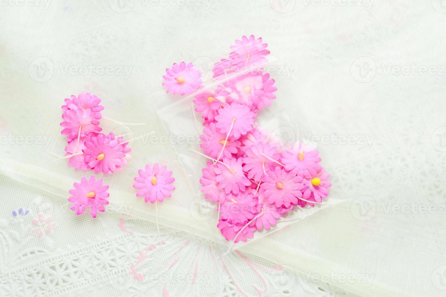 flores de papel artesanal em fundo de tecido branco, rosa e amarelo, decoração para cartão de convite. foto