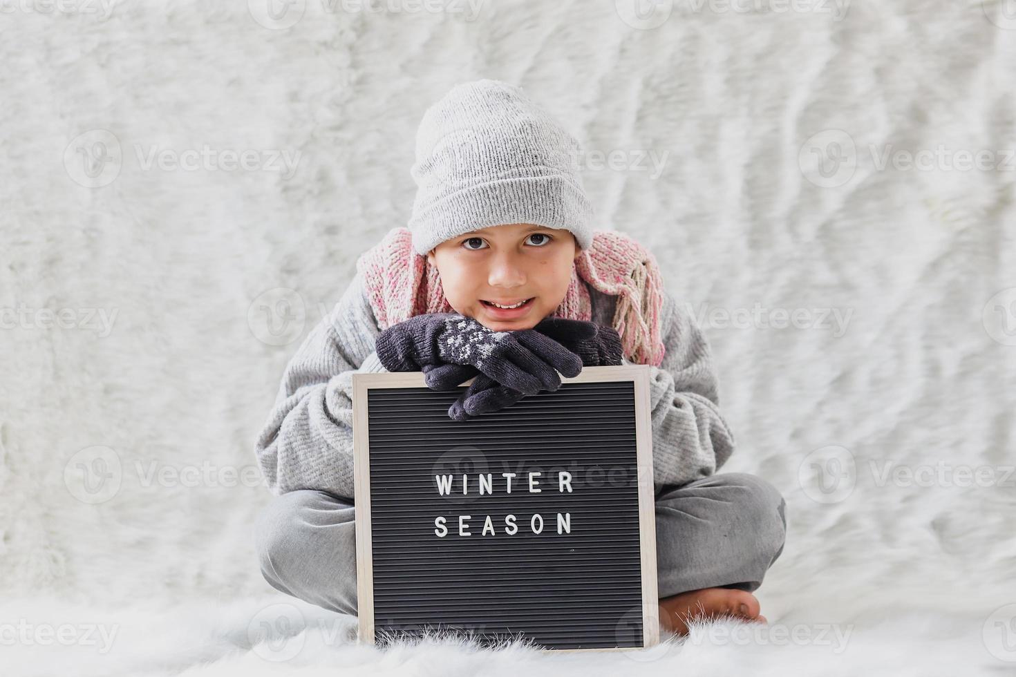 um menino vestindo roupas de inverno dá as boas-vindas à temporada de inverno alegremente foto