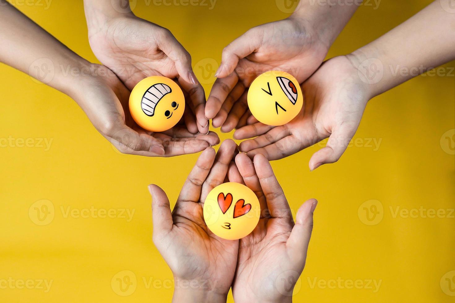 mãos de pessoas segurando emoticons de sorriso feliz e amor para o conceito de união foto
