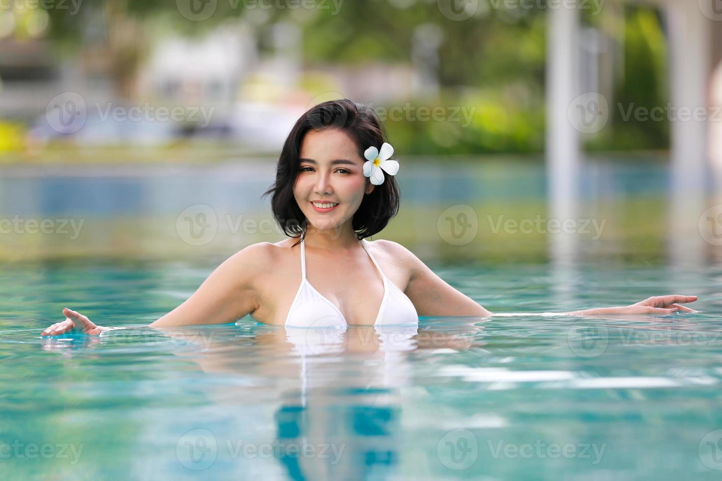 retrato de biquíni jovem sorridente em pé na piscina foto