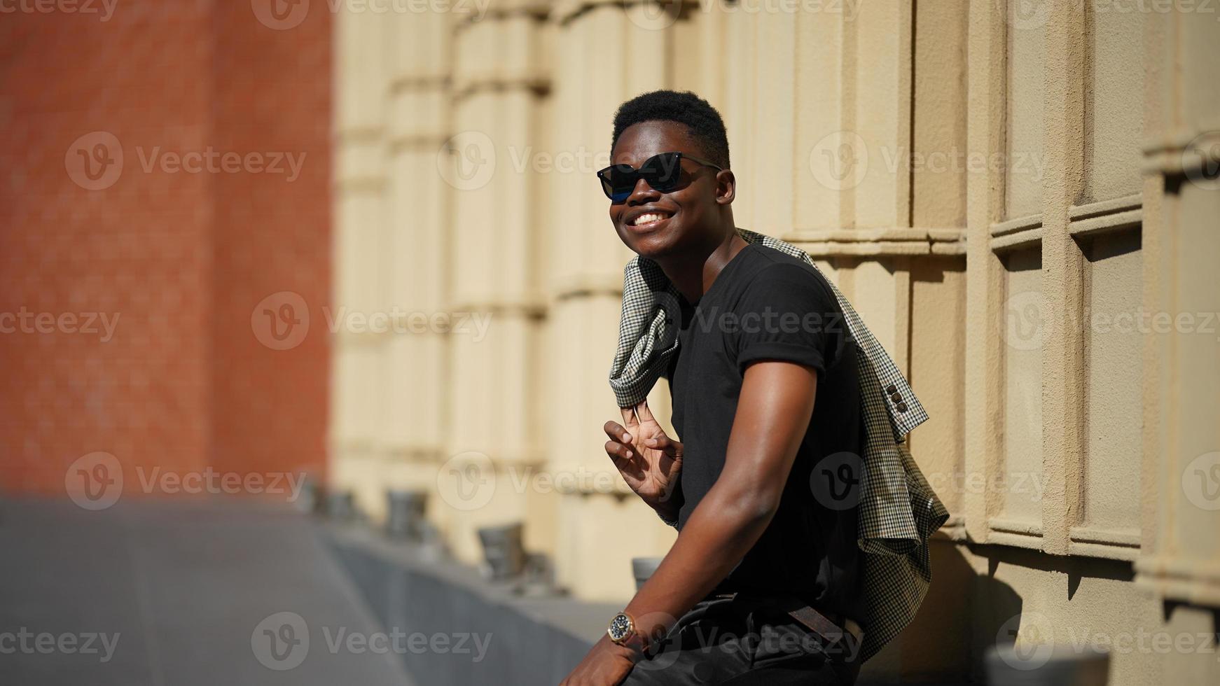 homem afro-americano se divertindo andando no centro da cidade - cara jovem feliz aproveitando o tempo um pôr do sol ao ar livre - estilo de vida da geração milenar e conceito de atitude positiva das pessoas foto