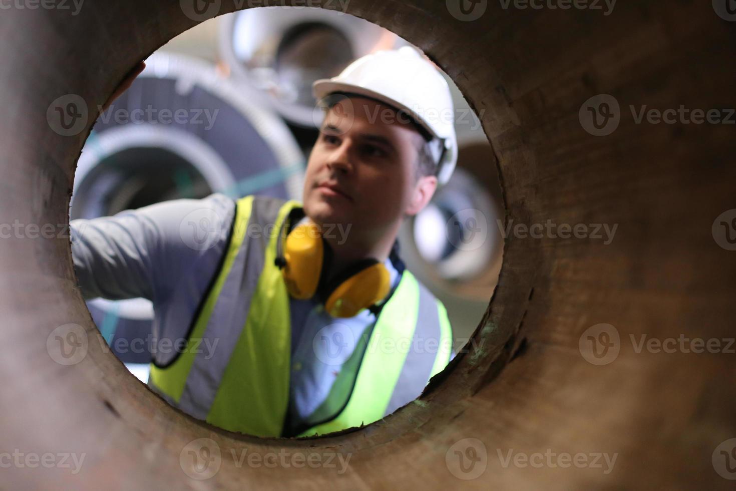 engenheiro industrial de homens usando um capacete de segurança em pé em uma fábrica industrial pesada. a manutenção procurando trabalhar em máquinas industriais e verificar a configuração do sistema de segurança na fábrica. foto